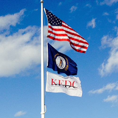 Nylon American Flag - Beacon® flying on a flagpole against a partly cloudy blue sky with two additional flags below it.