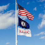 Nylon American Flag - Beacon® flying on a flagpole against a partly cloudy blue sky with two additional flags below it.