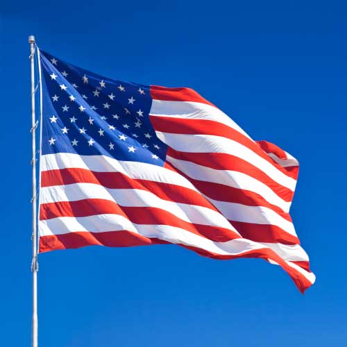 Nylon American Flag - Beacon® waving in the wind against a clear blue sky, showing vibrant red, white, and blue colors.