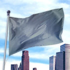 Gray solid colored flag made of durable fabric flying on a pole above city buildings, Solid Colored Flags - Premier Nylon