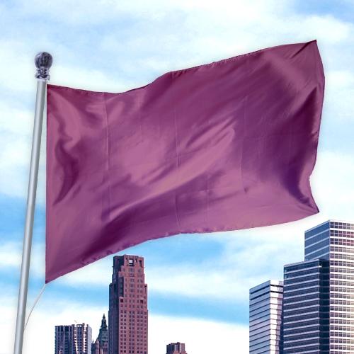 A solid maroon flag made of nylon flying on a pole above a city skyline in daylight, showcasing the Solid Colored Flags - Premier Nylon.