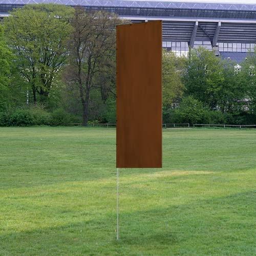 Solid Tall Advertising Flags with a tall, rectangular brown flag mounted on a metal pole set on a grassy field near trees and a stadium.