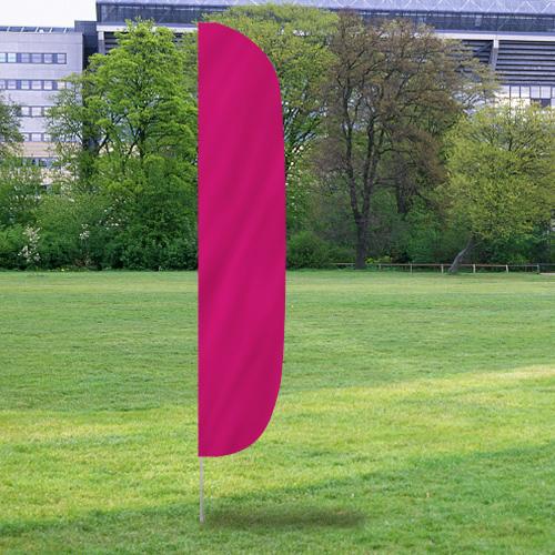 Solid Color Flutter Flags in bright magenta standing on a green grassy field with trees and buildings in the background.