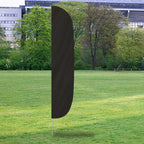Solid Color Flutter Flags in black standing upright on a grassy field with trees and buildings in the background.