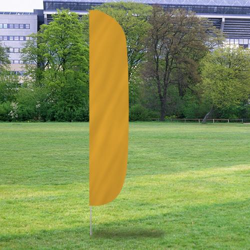 Solid Color Flutter Flags in gold color standing on a grassy field with trees and office buildings in the background.