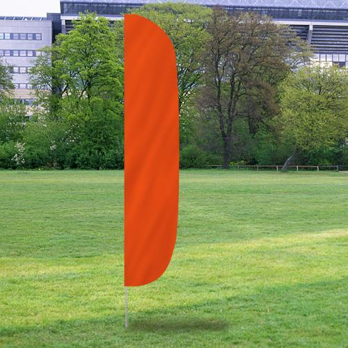 Solid Color Flutter Flags in bright orange set up outdoors on a grassy field with trees and buildings in the background.
