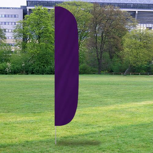 Solid Color Flutter Flags standing upright in a grassy park area with purple fabric fluttering gently in the breeze.