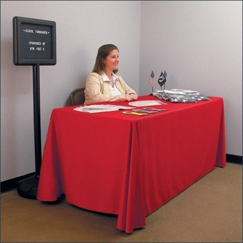 Woman sitting at a table covered with a red Solid Table Throws fabric, with small flags and documents on top in a meeting room setting